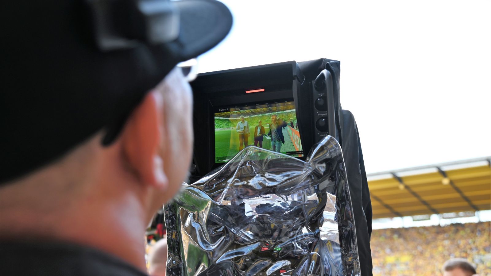 Blick durch das Objektiv einer TV-Kamera im Fußballstadion