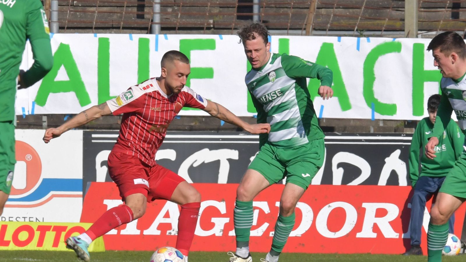 Fortuna Kölns Mittelfeldspieler Stipe Batarilo-Cerdic (rotes Trikot) im Zweikampf mit Julian Schauerte vom FC Gütersloh.