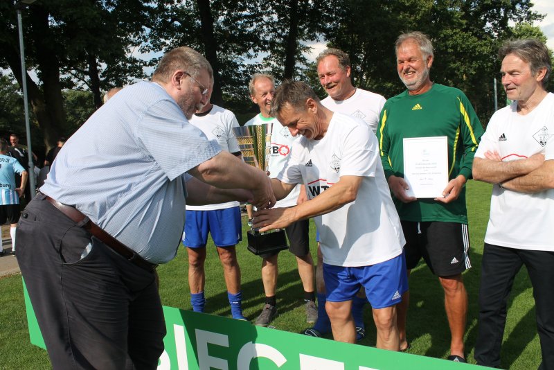 Wolfgang Jades, Vorsitzender des WDFV-Fußballausschuss (links), gratulierte dem Team von DJK TuS Stenern / VfL 45 Bocholt zum Sieg bei den Ü60-Herren.